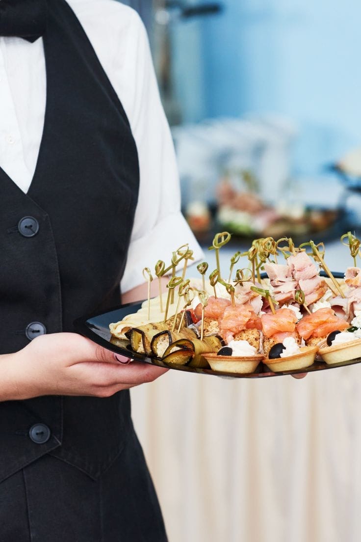 Mesero presentando bandeja de canapés y bocadillos