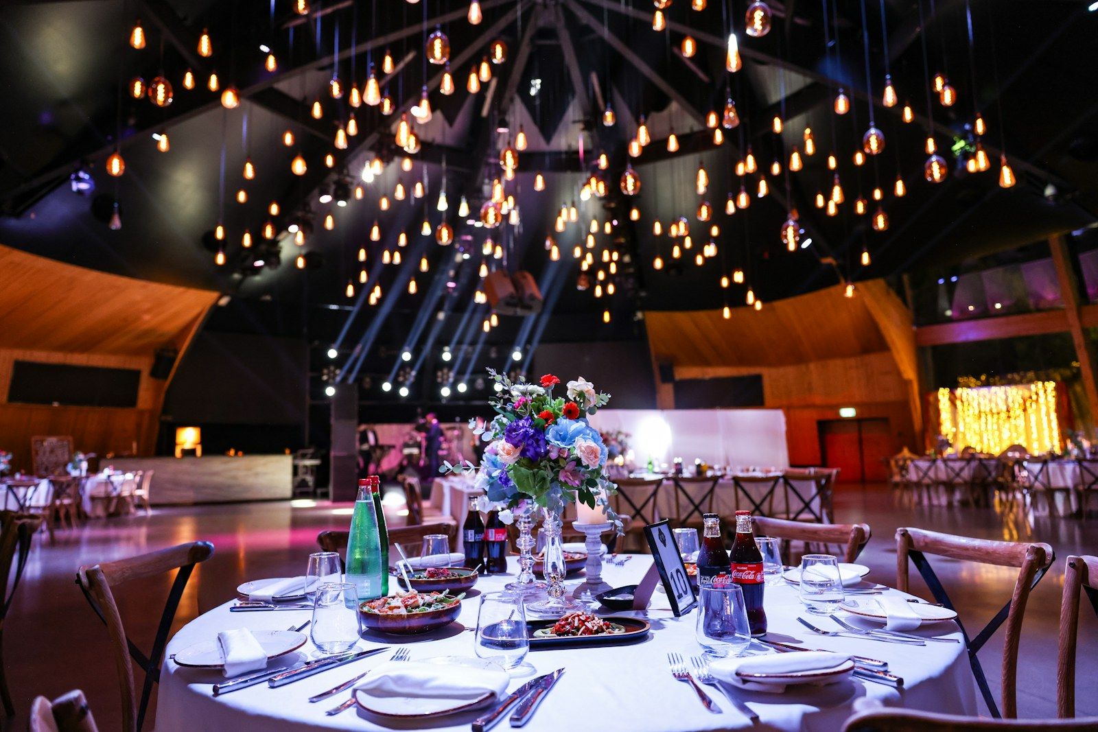 Salón de celebración con luces colgantes y mesas montadas