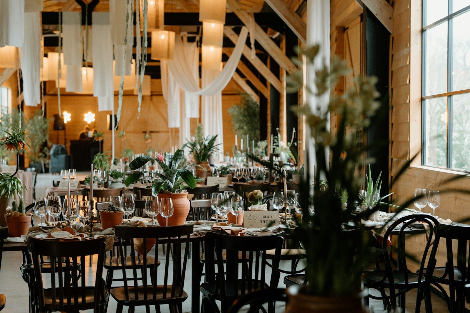 Recepción de boda con mesas largas, velas y telas colgantes