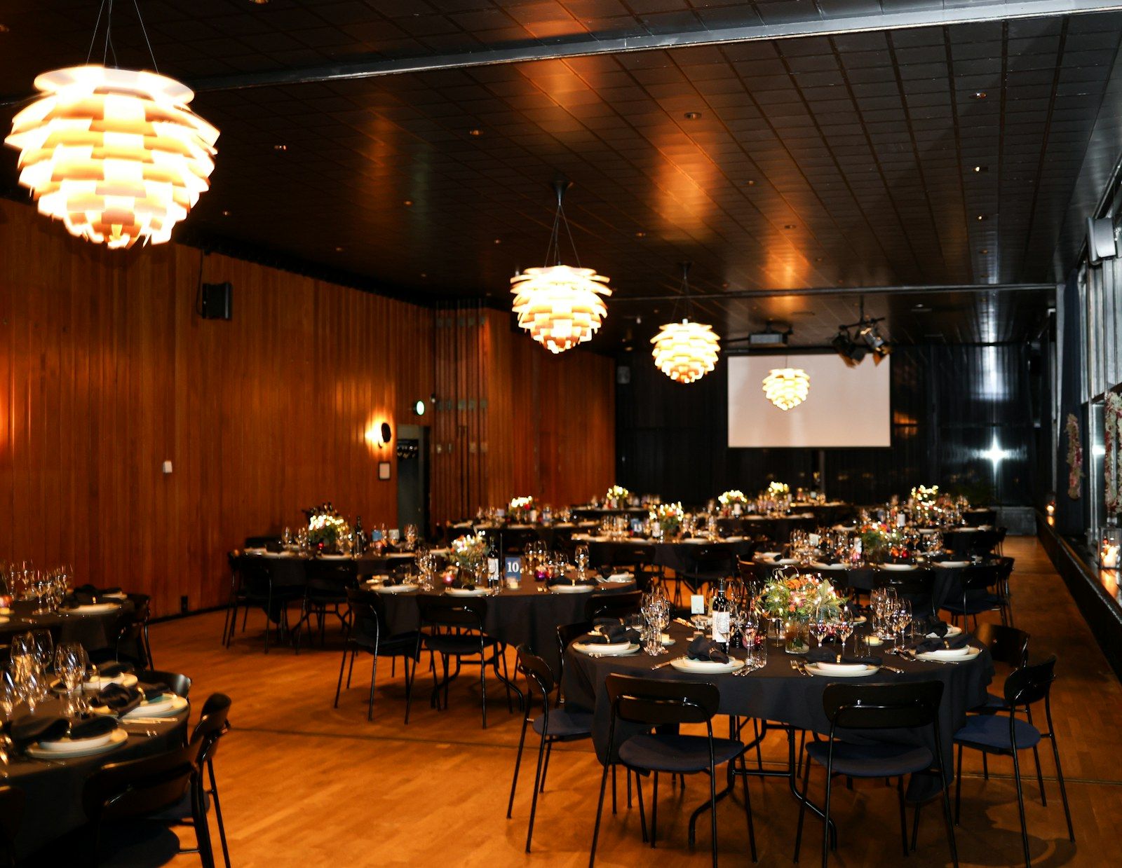 Montaje formal de evento con mesas redondas e iluminación cálida